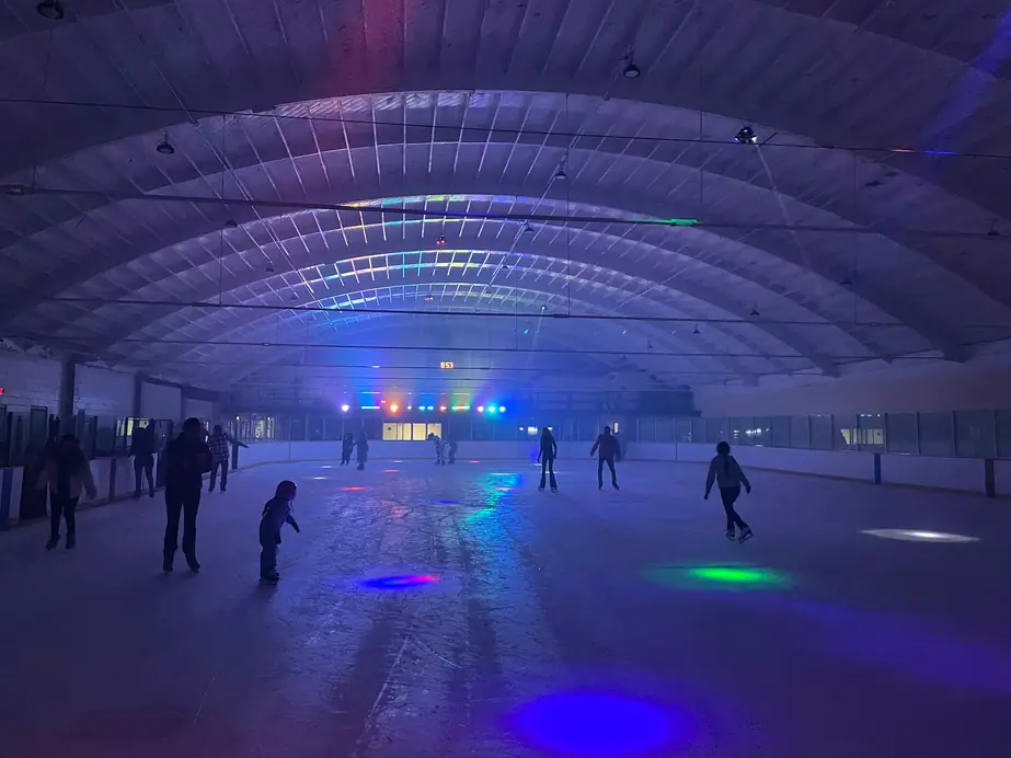 Disco night at the Ontario rink, colored spots on the ice under the arched roof