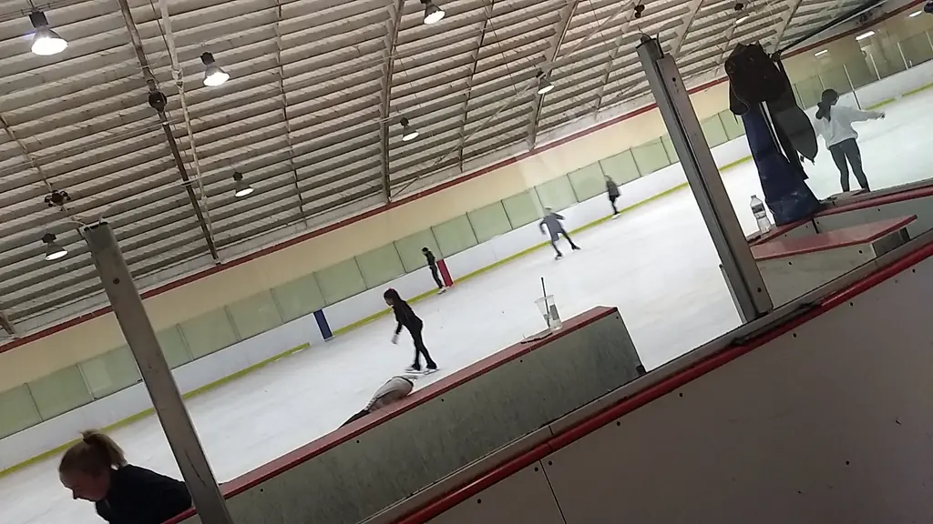 Skaters practicing on the Ontario ice, seen through the boards