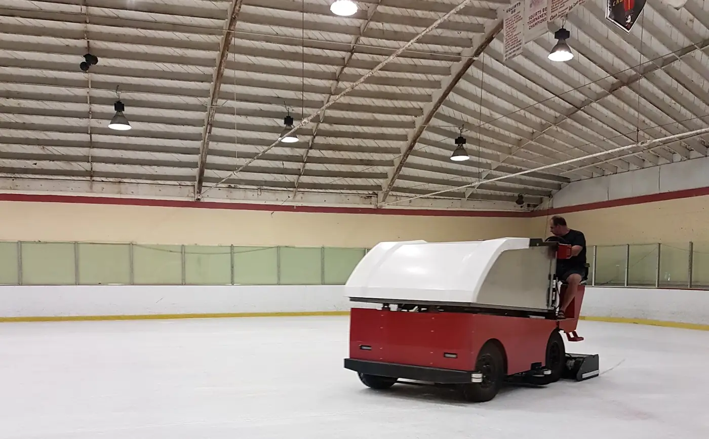 The rink's red resurfacer laying fresh ice under the barrel-vault trusses and tournament banners