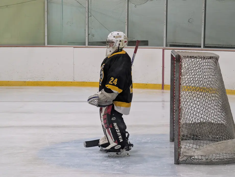 A young goalie in full mask beside the net on the Ontario ice